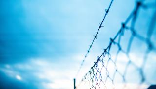 Barbed wire fence under blue skies