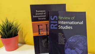 A copy of RIS and a copy of EJIS on a white bookcase next to a small plant