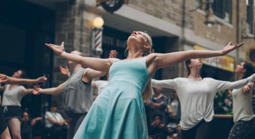 female actor in a blue dress with arms outstretched