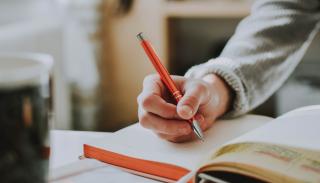 A hand writing in an open notebook