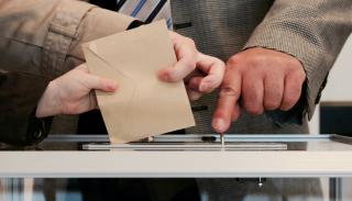 Image of people putting a voting ballot in a box