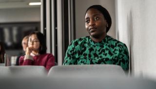 A BISA ECR/PG day delegate in a green and black dress listening to a talk