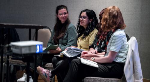 3 women sitting in a half circle with books on their laps