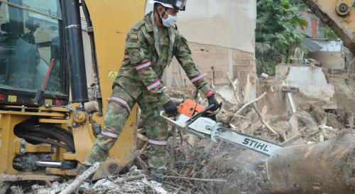 Man in camo cutting wood with a chainsaw 